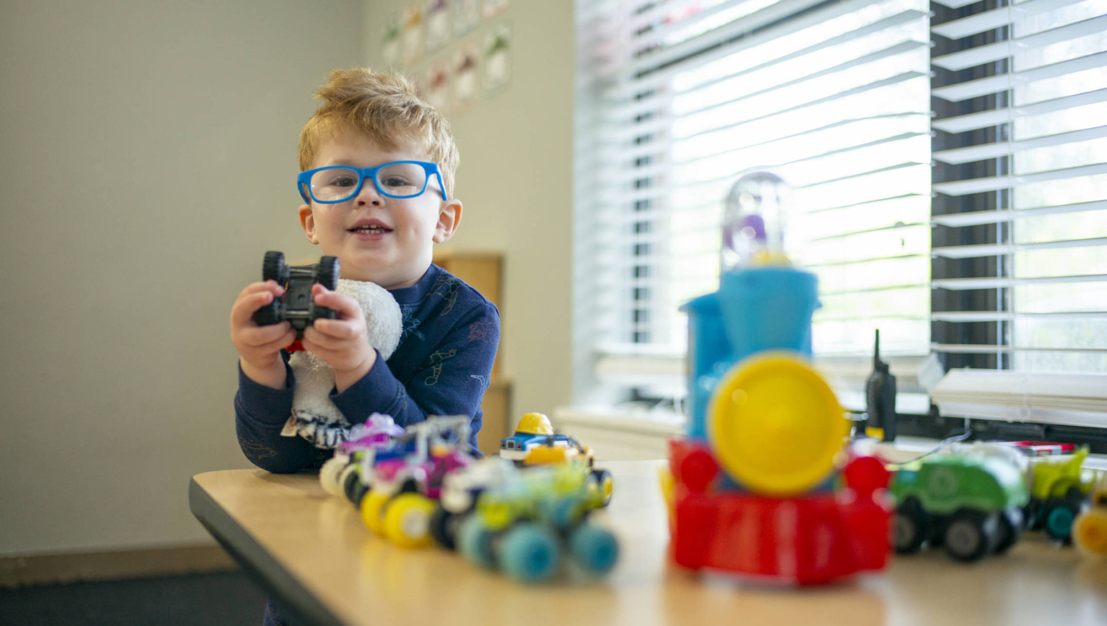 Boy in glasses playing with toys
