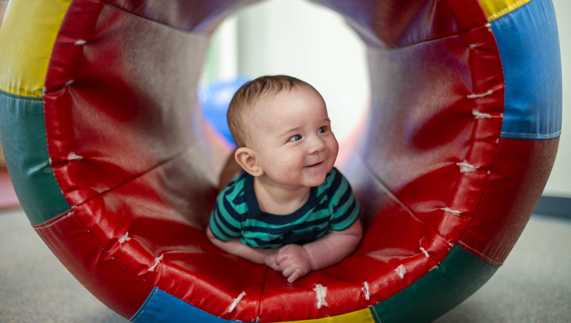 Baby smiling on rolled play mat